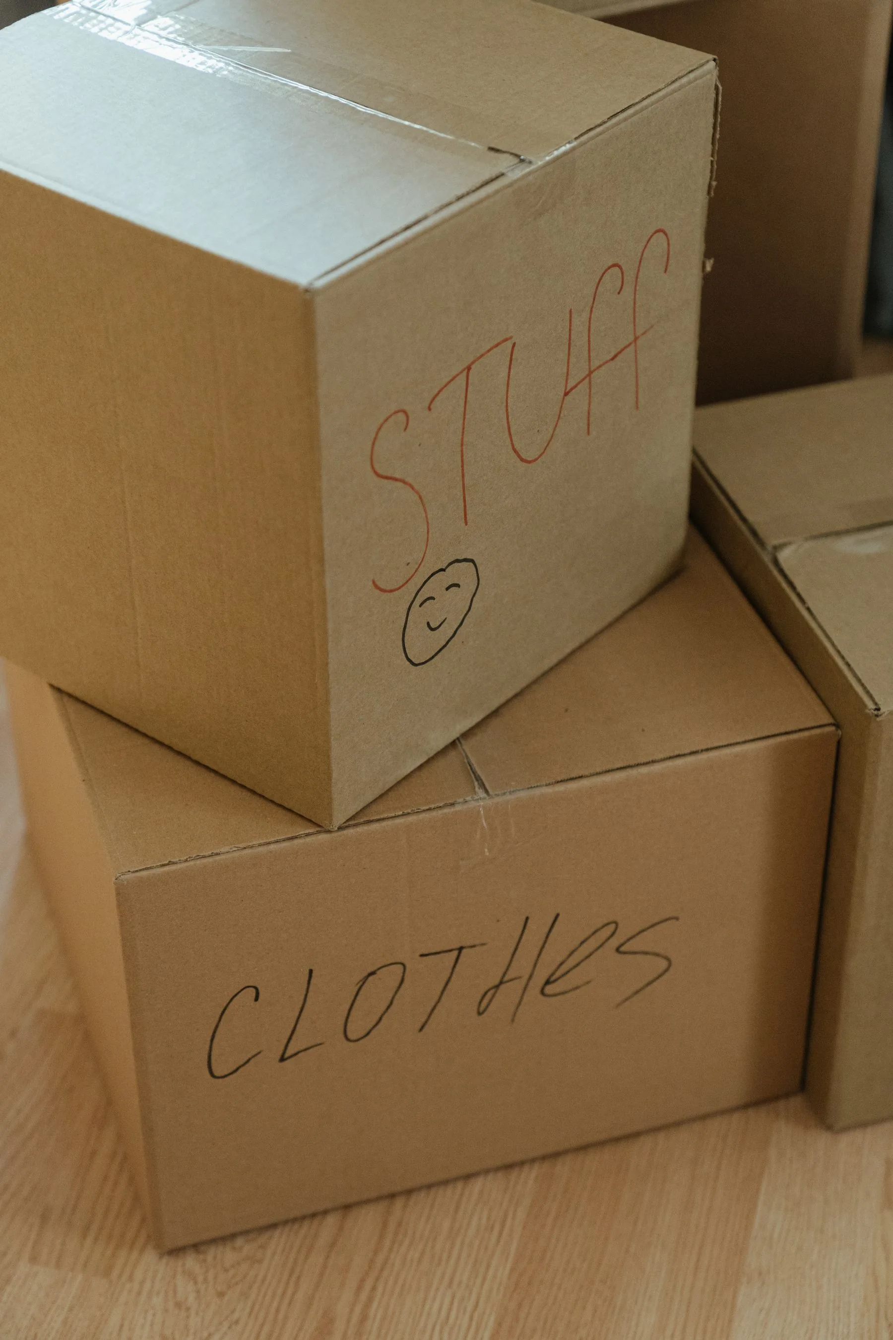 Cardboard moving boxes labeled by room and stacked before a move