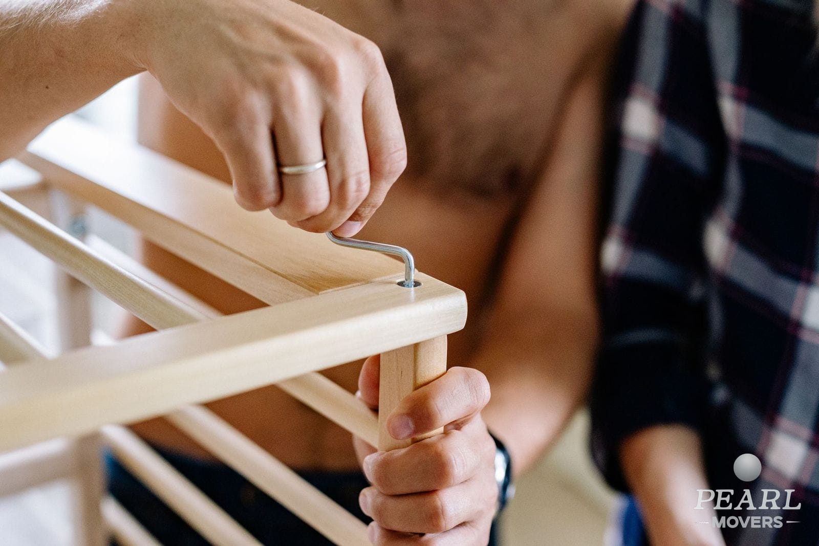 A person removing the legs from a wooden table with hand tools
