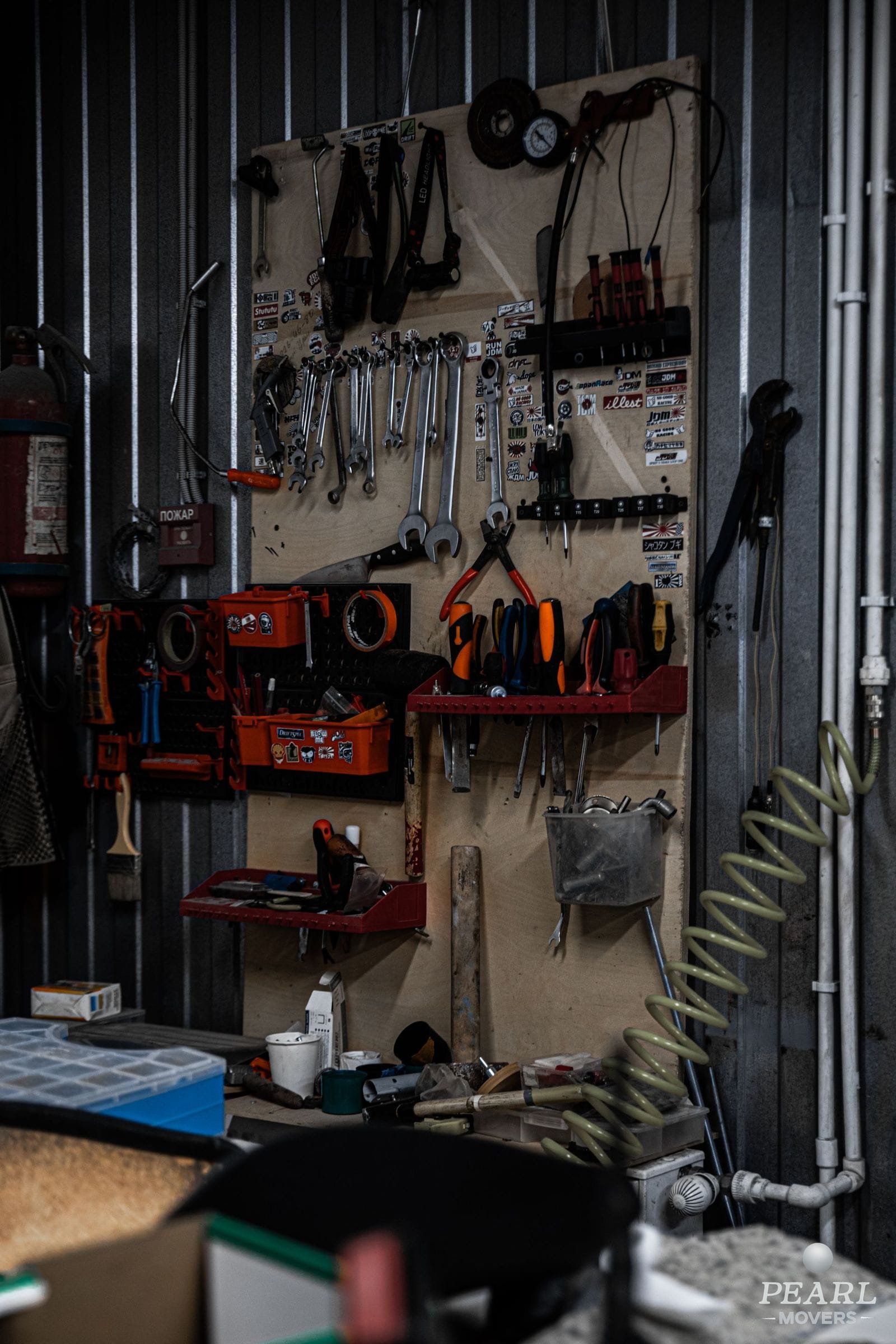 A garage workshop with tools on a workbench and wall storage