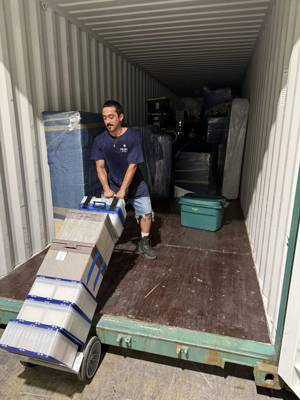 A Pearl Movers crew member wheeling labeled bins into a loaded container