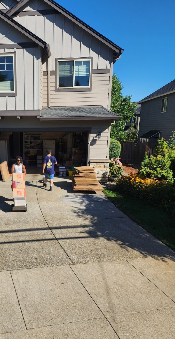 Pearl Movers crew wheeling boxes up the driveway of a larger suburban home