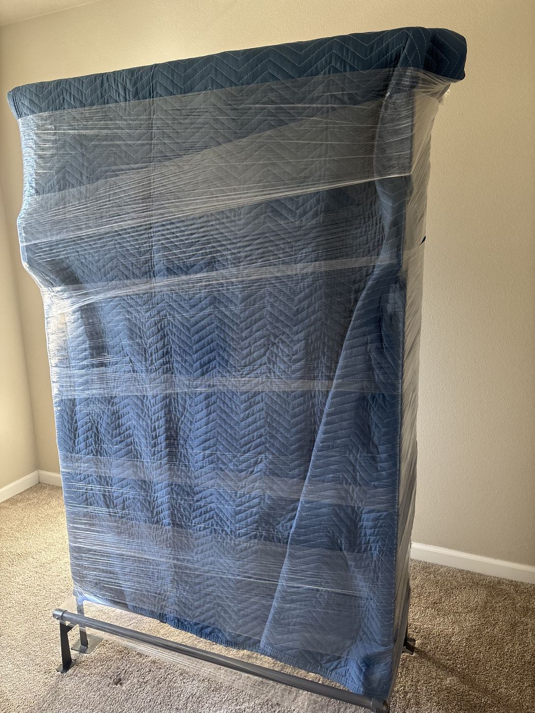 Large flat item wrapped in a moving blanket and secured with stretch wrap